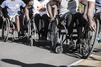 A group of men riding wheelchairs down a street.