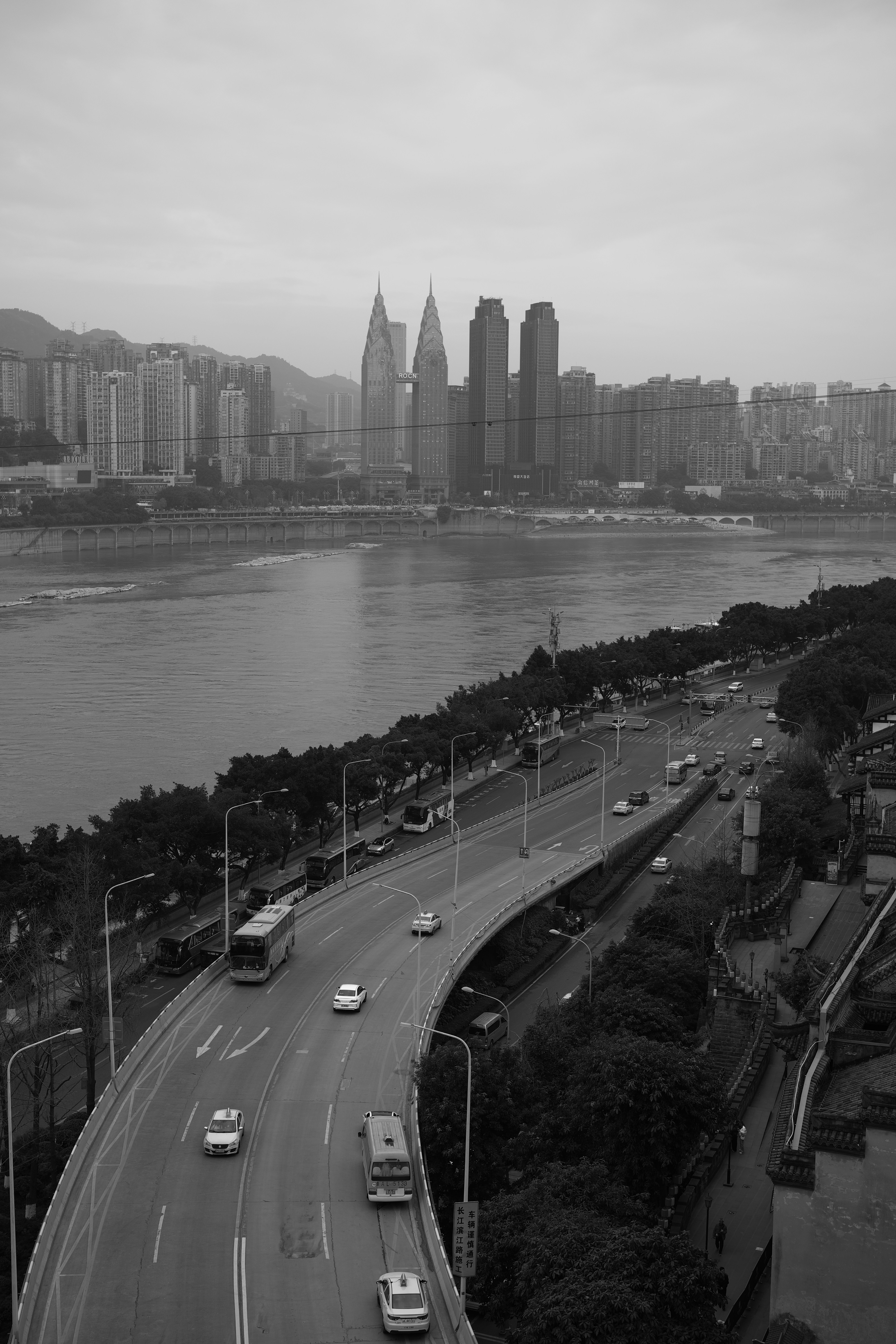 A black and white photo of a highway with a city in the background