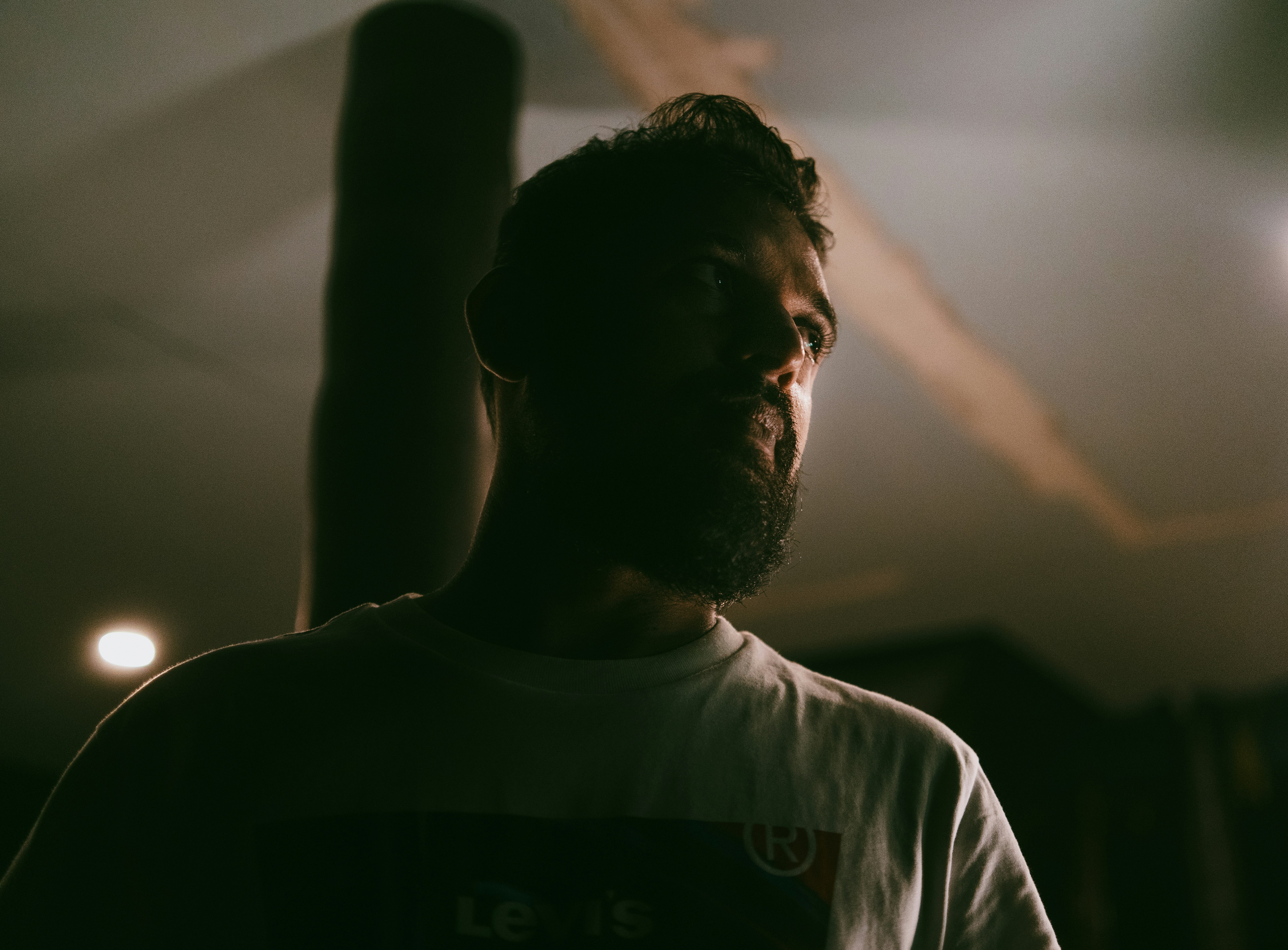 A man standing in a dark room holding a remote