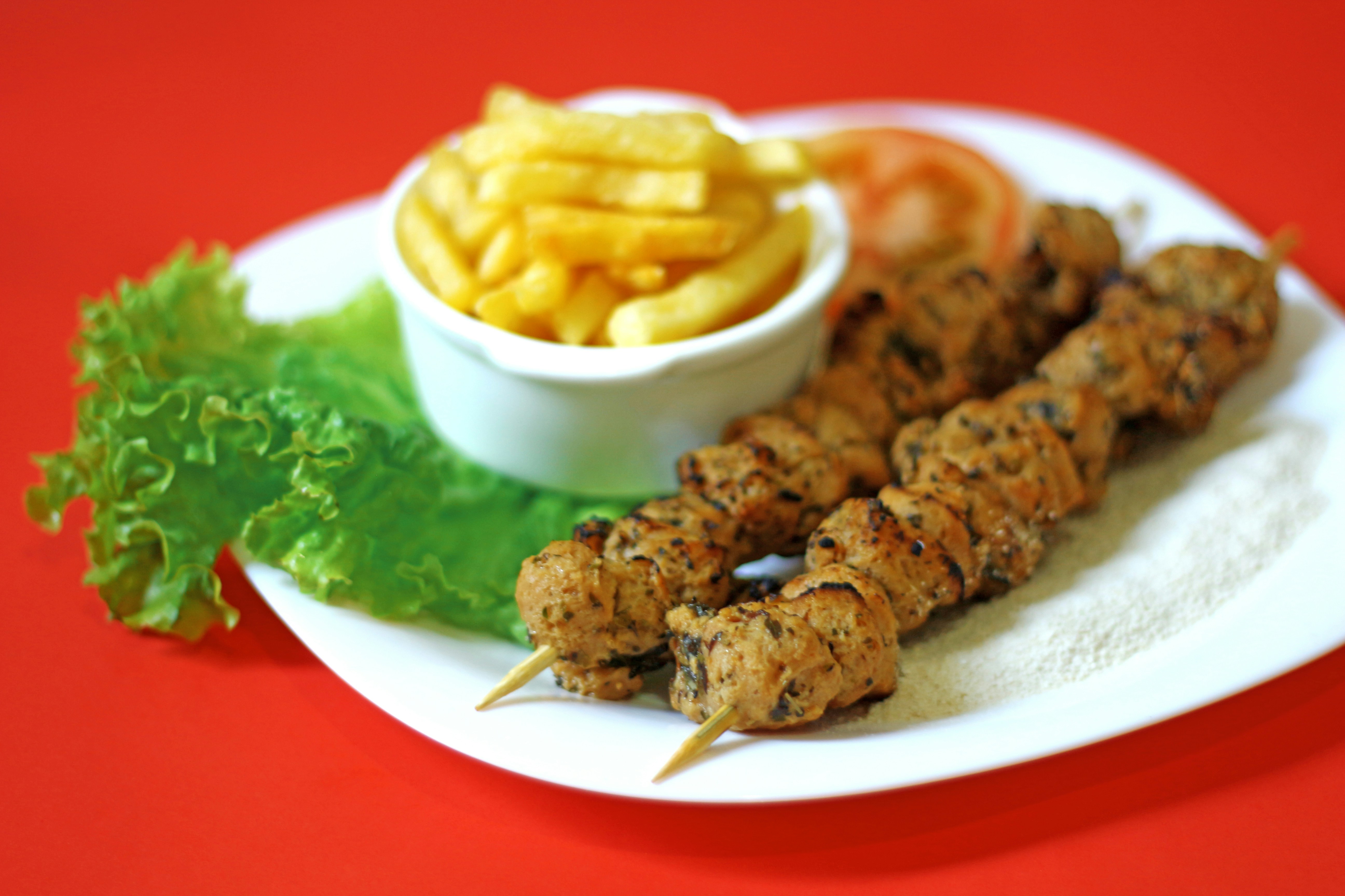 A white plate topped with kebabs and french fries