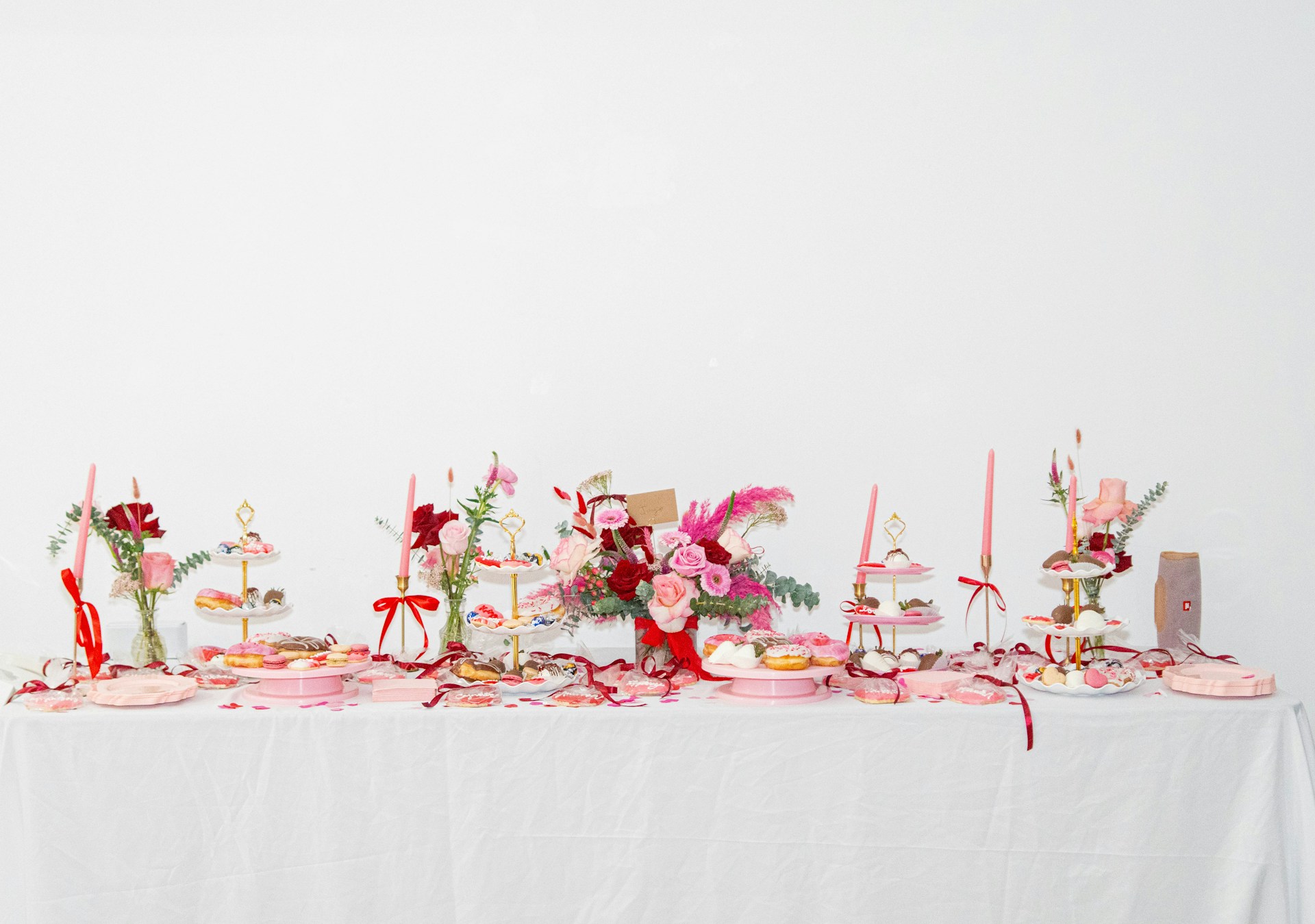 A white table topped with lots of pink flowers