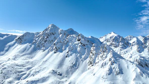 A mountain range covered in snow under a blue sky