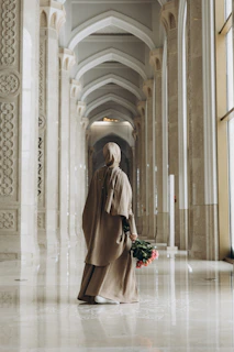 A woman standing in a hallway holding a bouquet of flowers