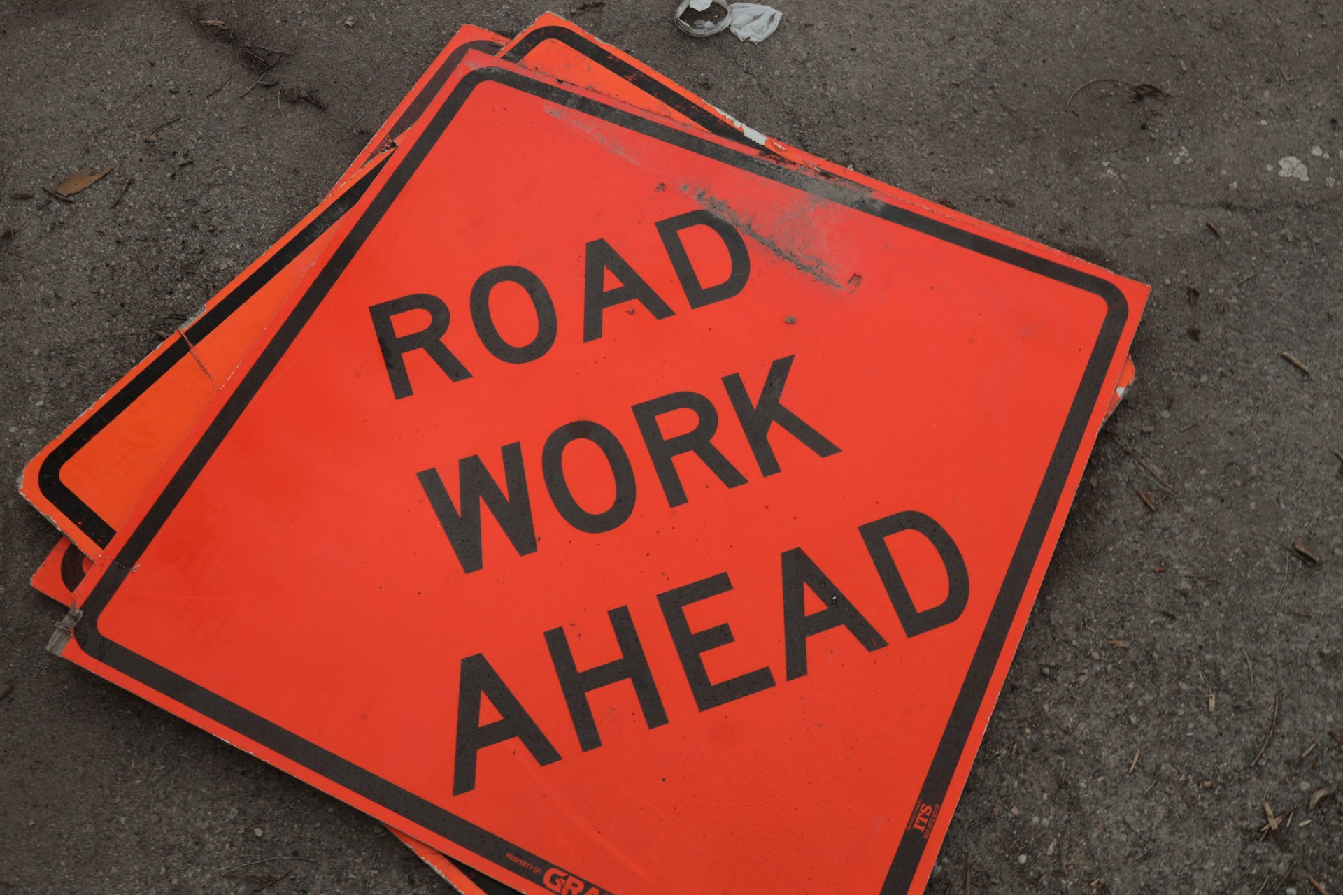 A road work ahead sign laying on the ground