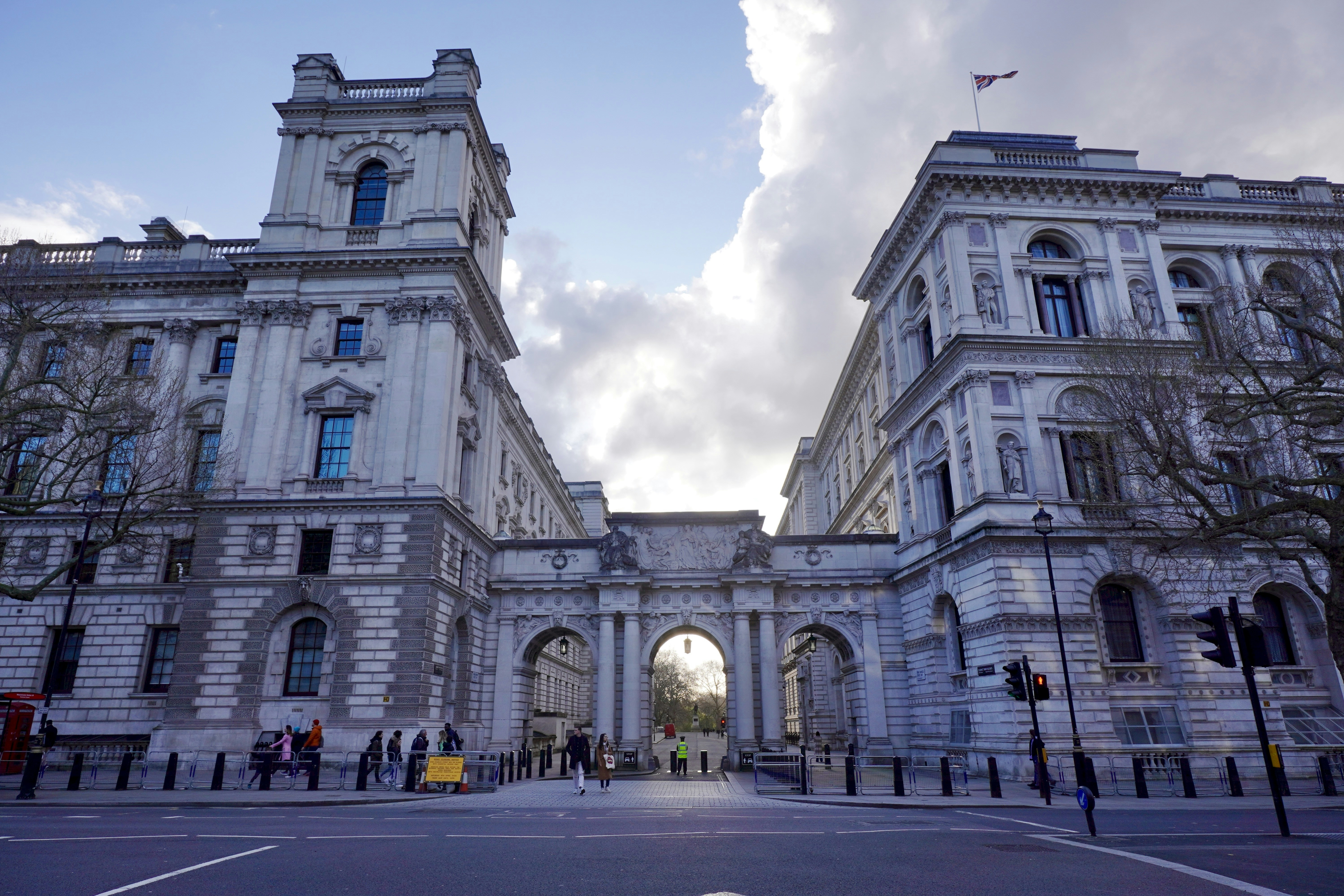 A large white building with a clock tower, The grand architecture of the Foreign, Commonwealth & Development Office in Whitehall, London, showcases its impressive neoclassical design. The historic archway leads towards St. James
