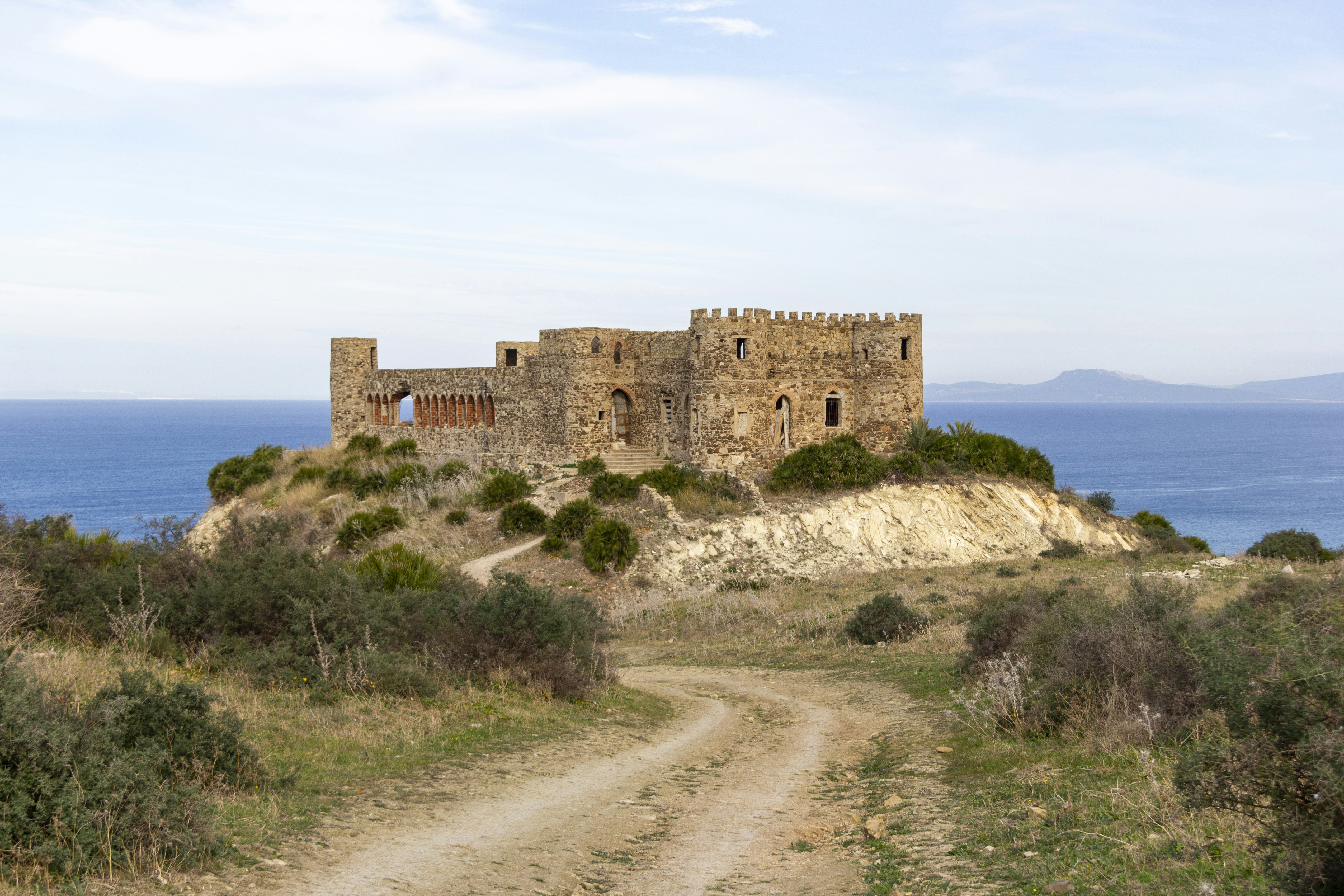Un camino de tierra que conduce a un castillo cerca del océano