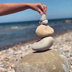 A person stacking rocks on a beach with the ocean in the background