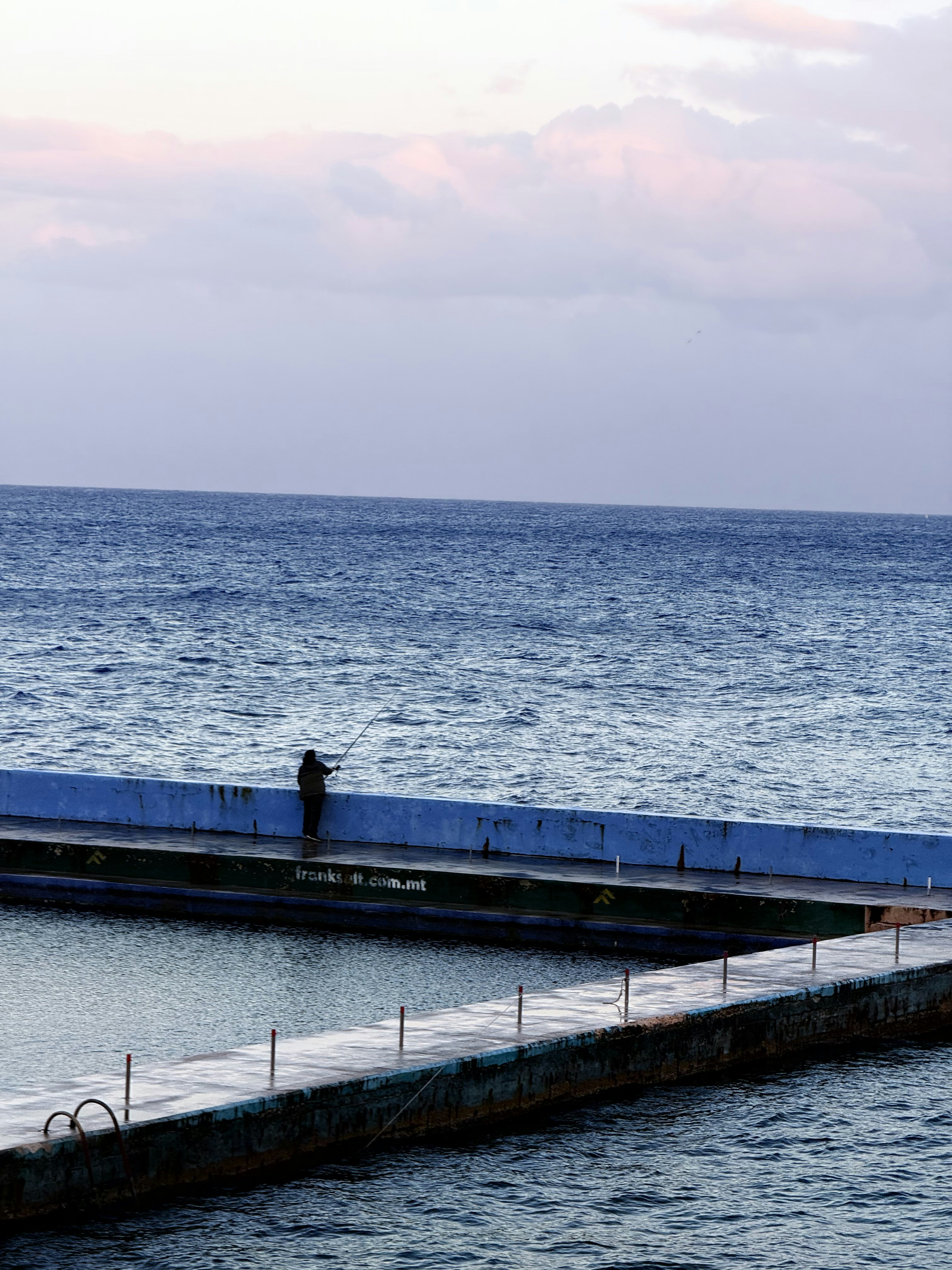 A person standing on a dock in the middle of the ocean