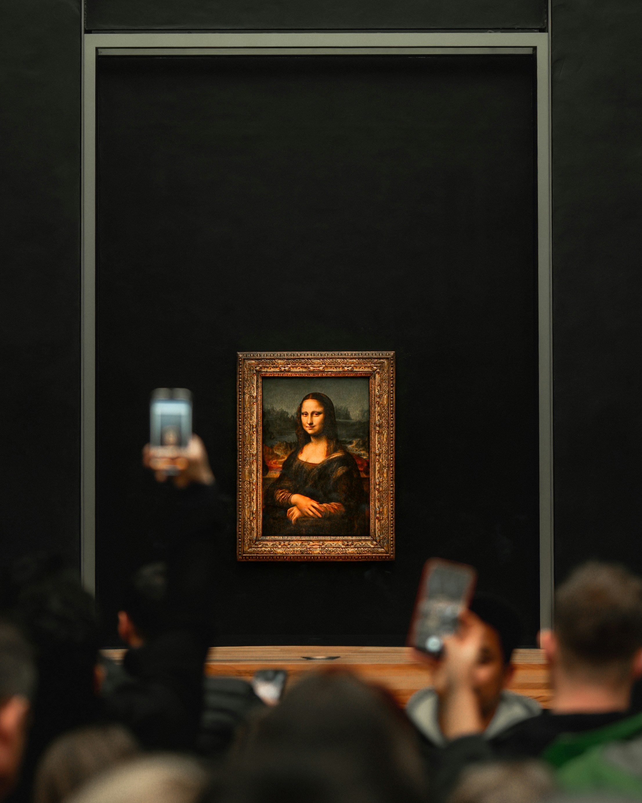 A group of people taking pictures of a painting