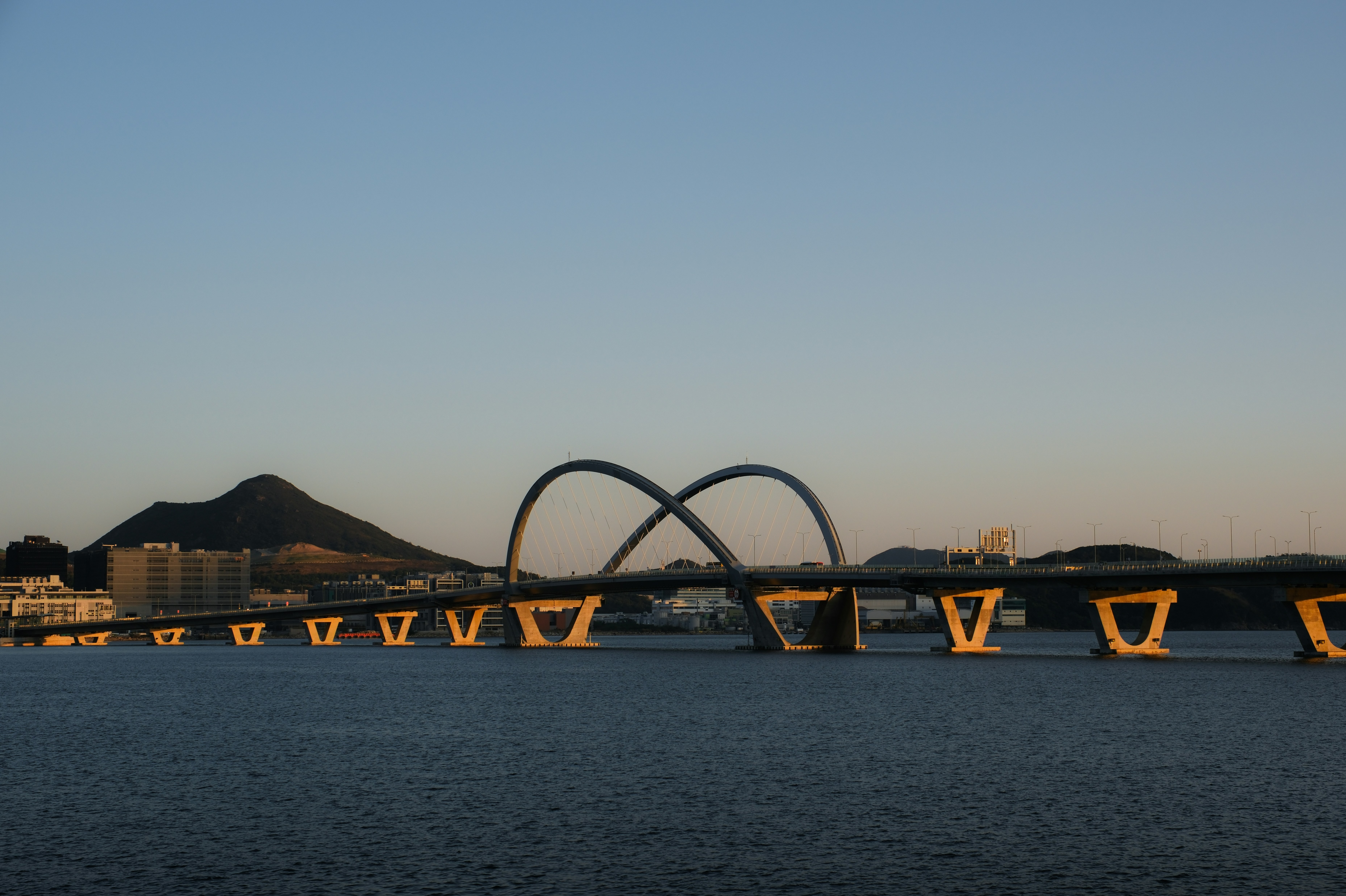 A bridge over a body of water with mountains in the background