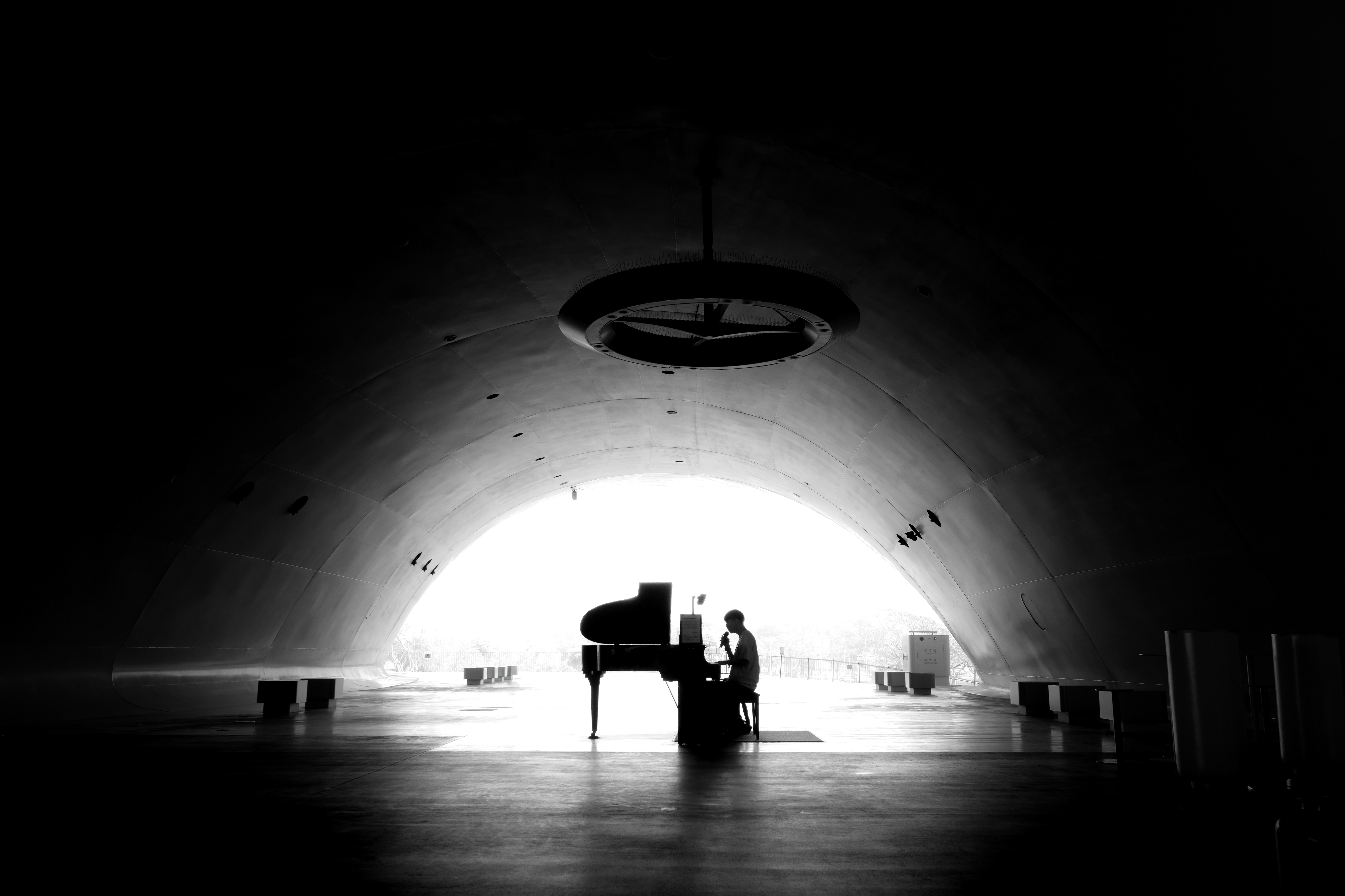 A man sitting at a piano in a dark tunnel