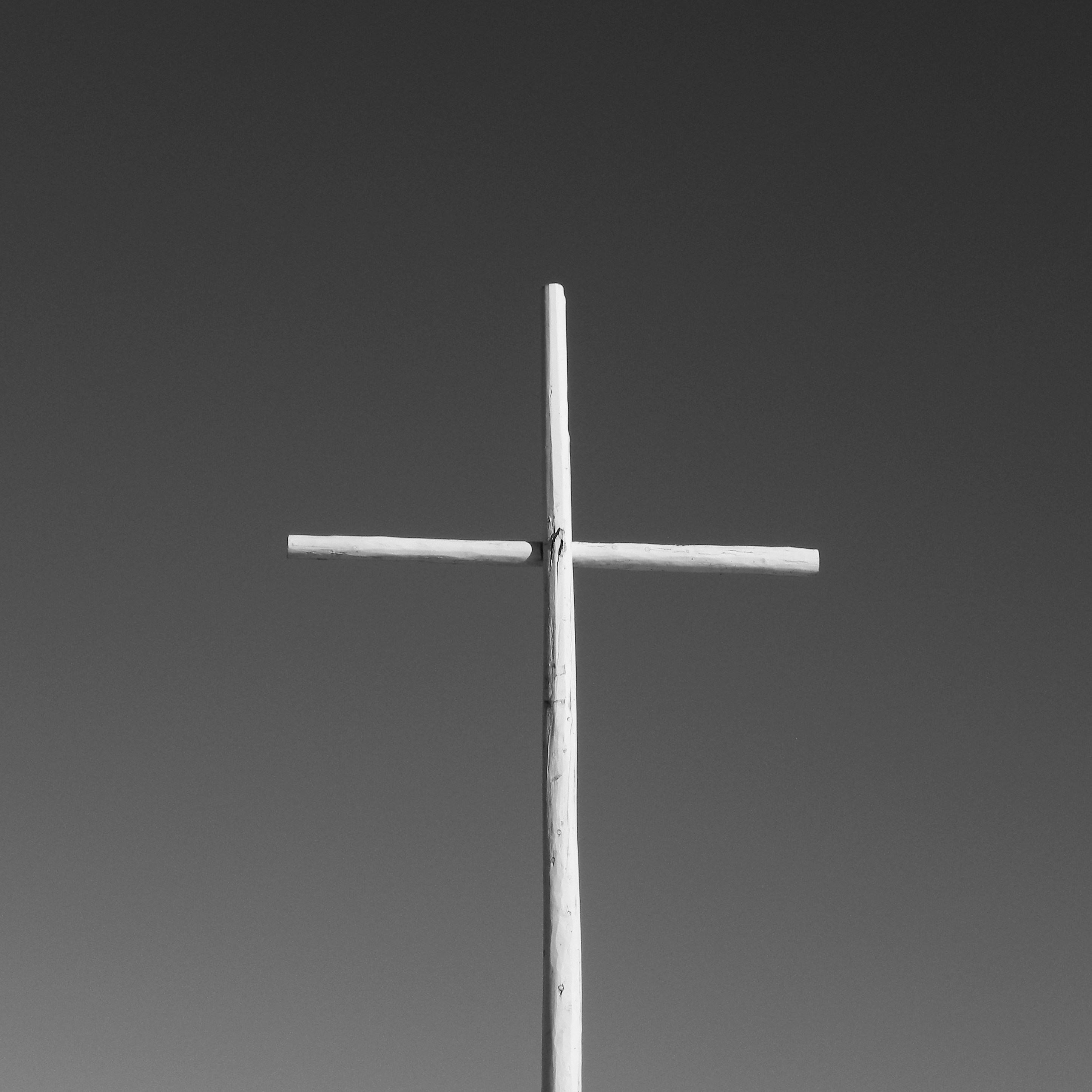 A black and white photo of a cross on a hill
