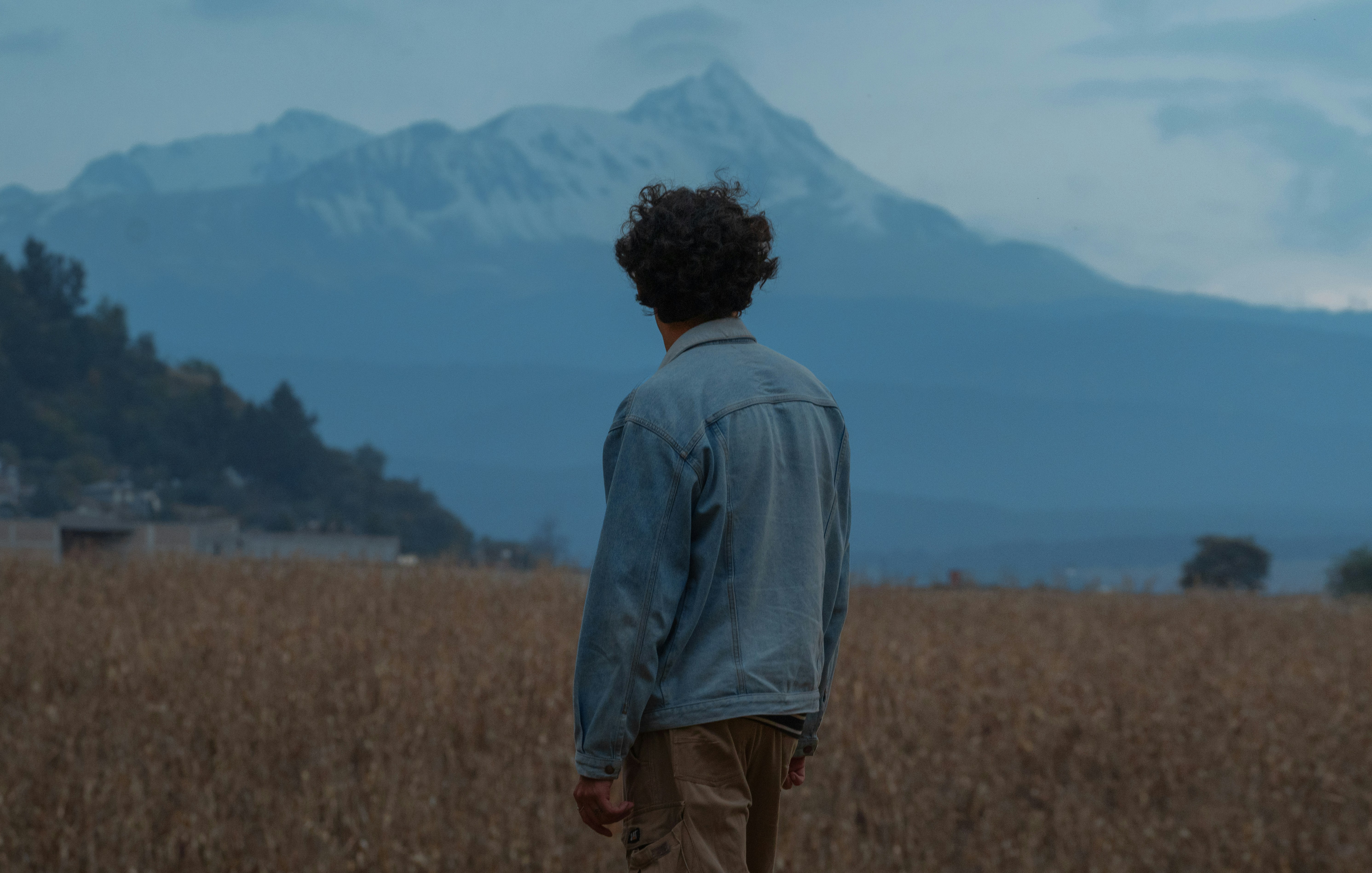 산을 배경으로 들판에 서 있는 남자
