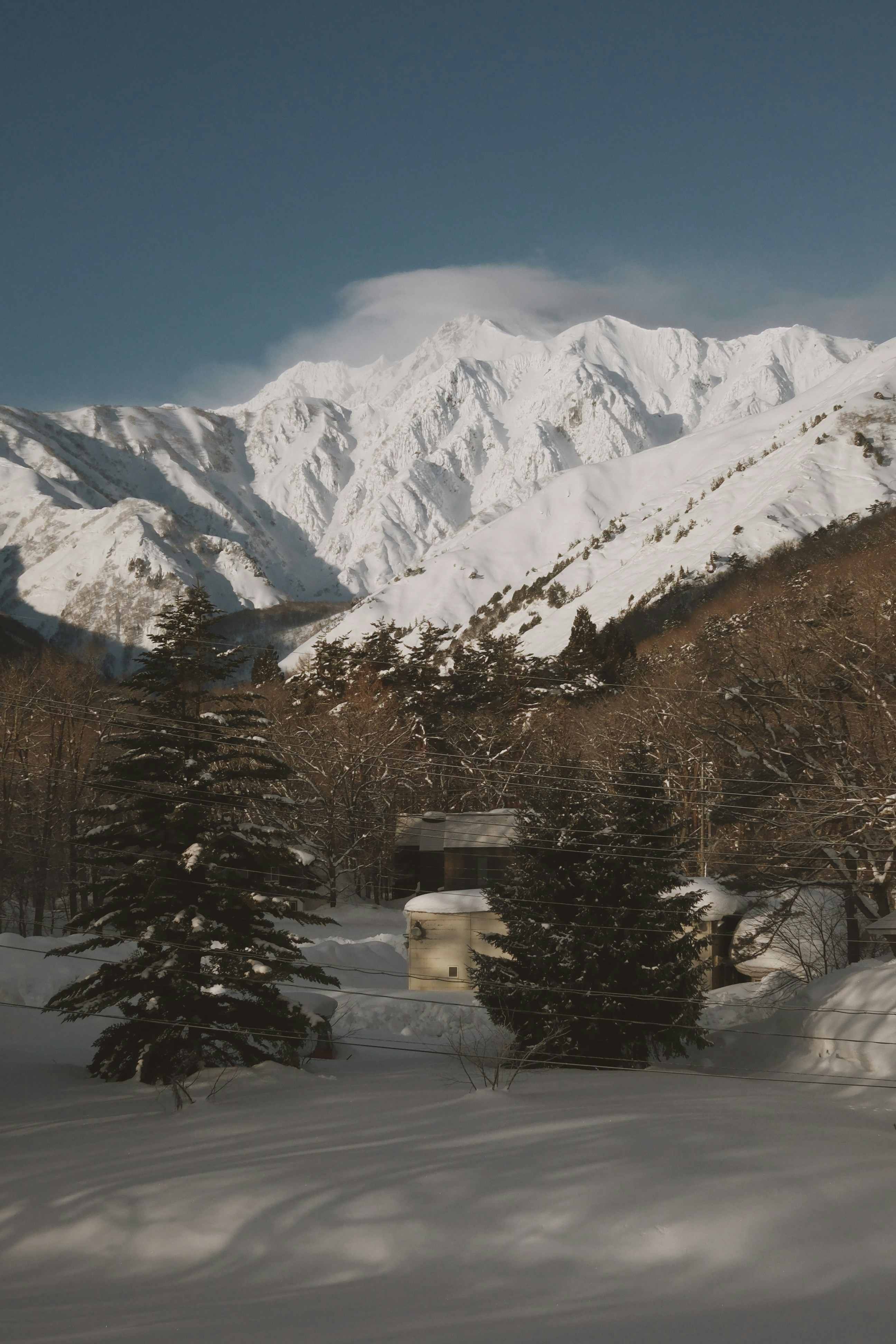 A snow covered mountain with a house in the foreground