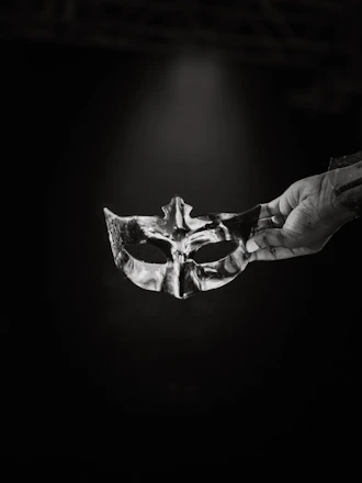A black and white photo of a person holding a mask