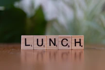 A wooden block spelling lunch on a table
