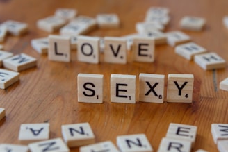 A wooden table topped with scrabble letters spelling love and sex