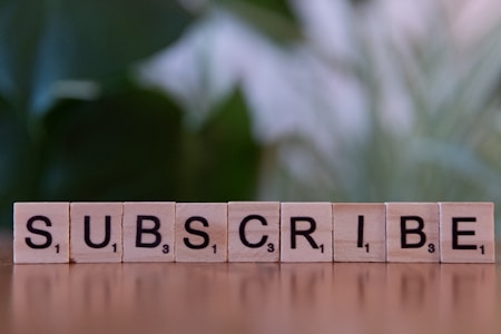 A wooden block spelling subscribe on a table