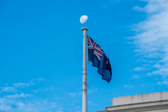 A flag flying in the wind on top of a building