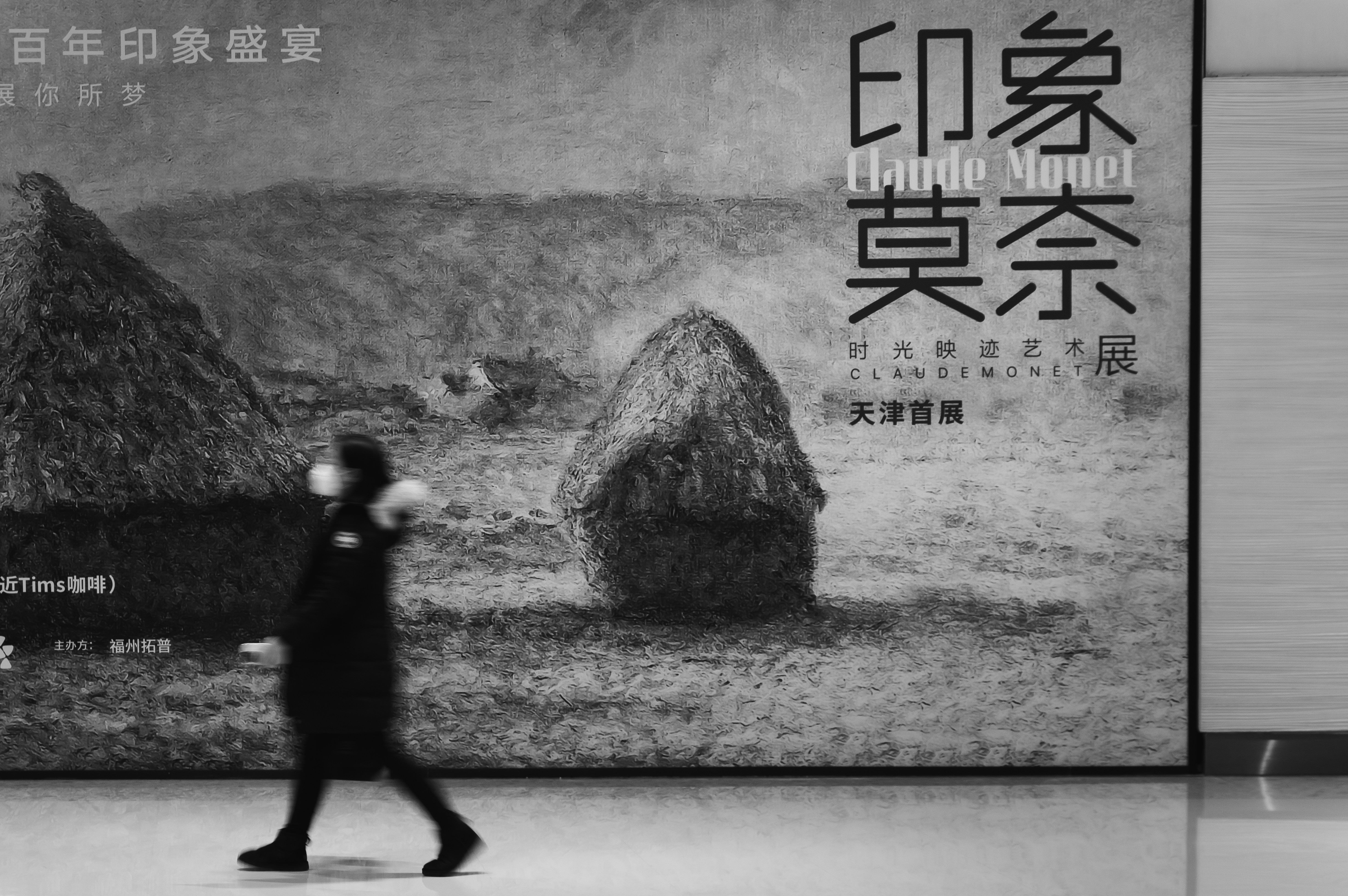 A man walking past a large painting on a wall
