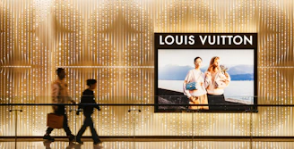 Two people walking past a louis vuitton advertisement