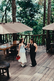 A couple of women standing on top of a wooden deck