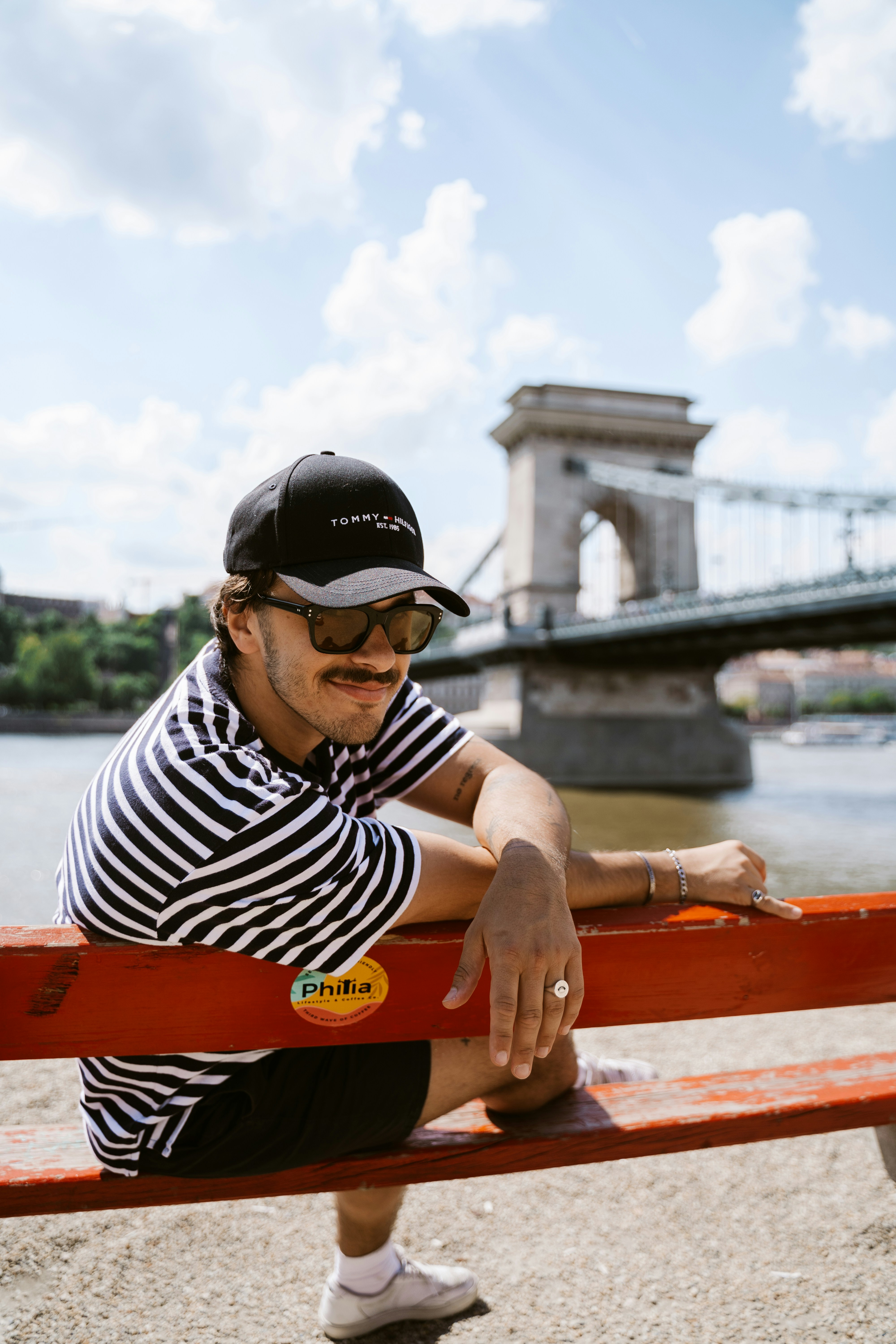 Un homme assis sur un banc rouge au bord d’une rivière