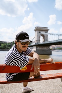 A man sitting on top of a red bench next to a river