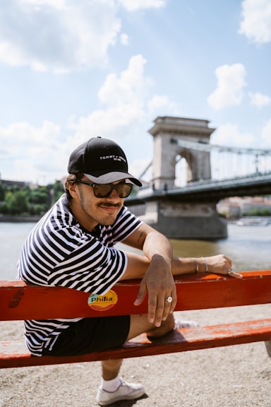 A man sitting on top of a red bench next to a river