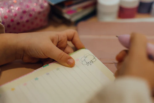 Student practising Arabic script by hand with pen and notebook