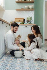A man and two girls are sitting on the floor with a cat