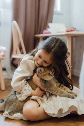 Niña abrazando a un gato en el suelo