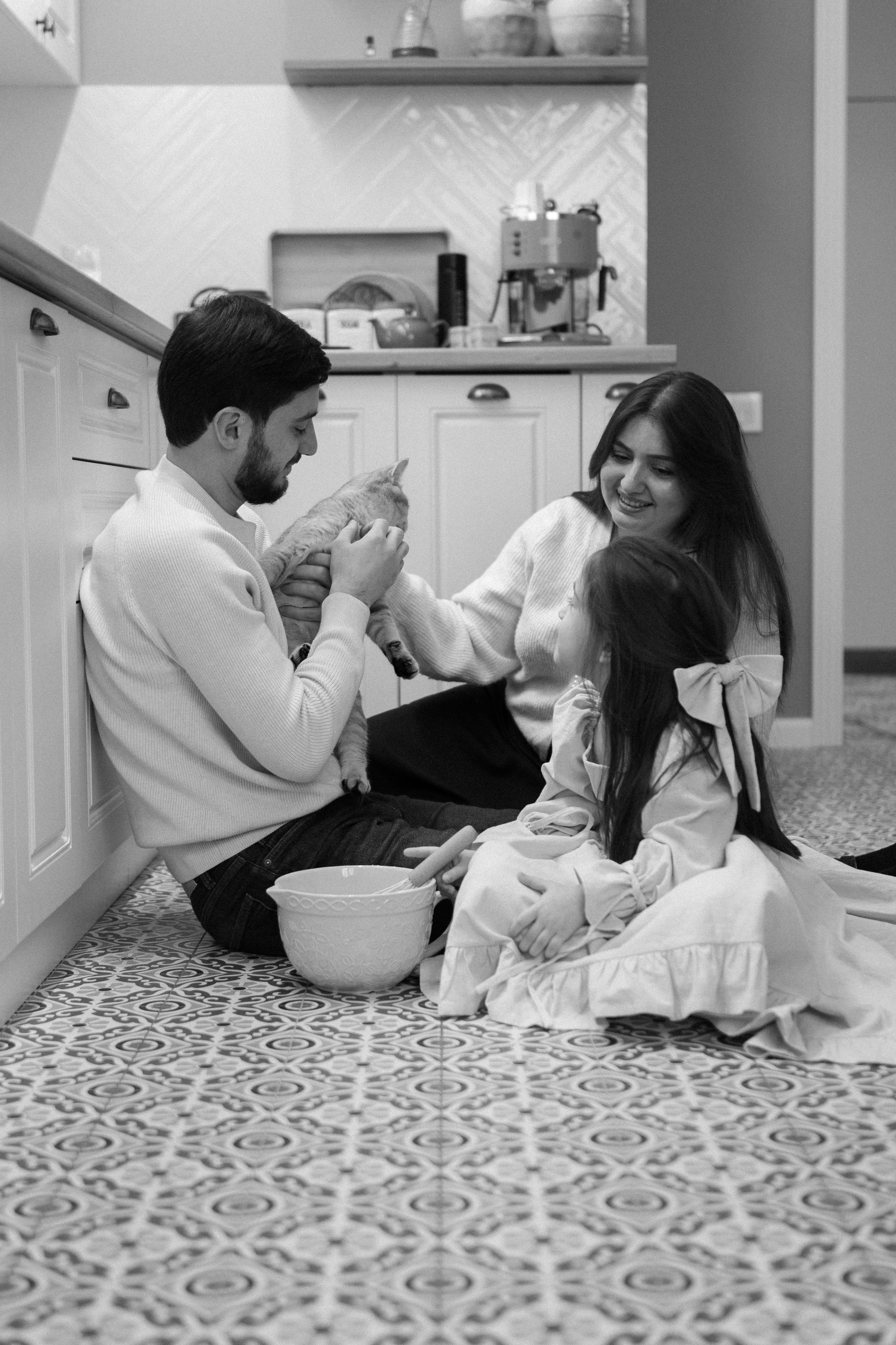 A man and a woman sitting on the floor in a kitchen