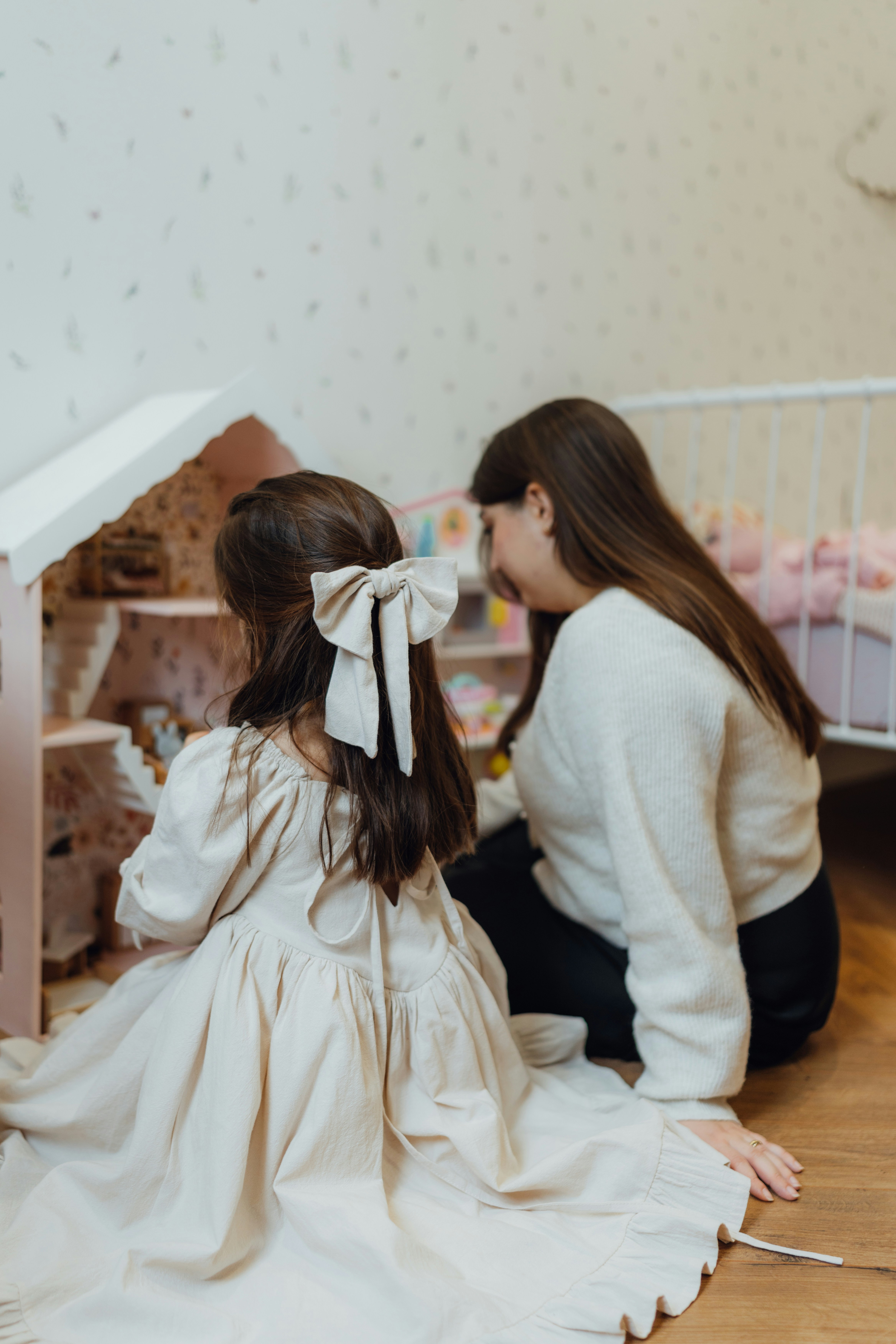 Two young girls sitting on the floor in front of a doll house