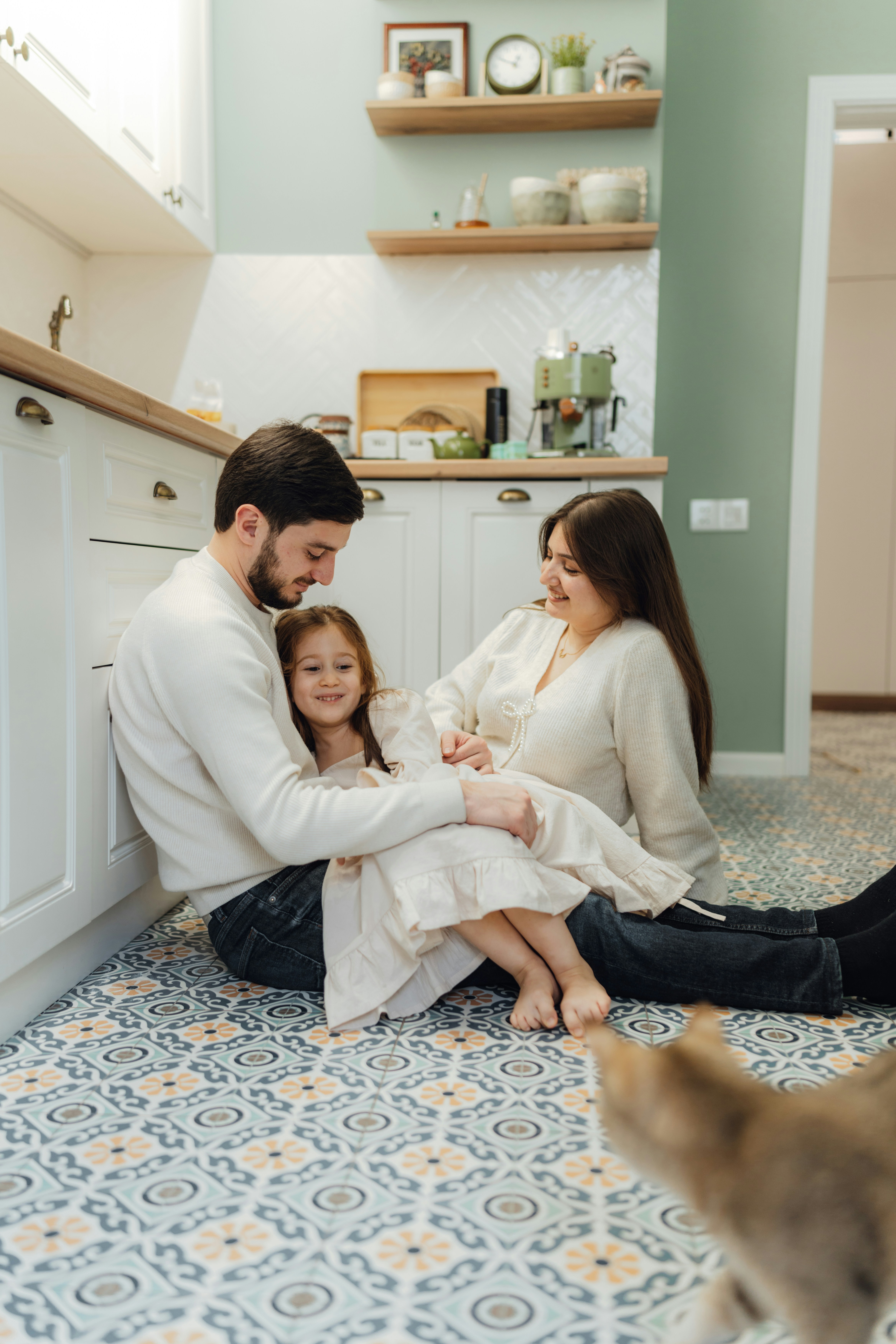 A family sitting on the floor in a kitchen