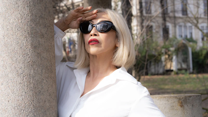 A woman wearing sunglasses leaning against a pillar