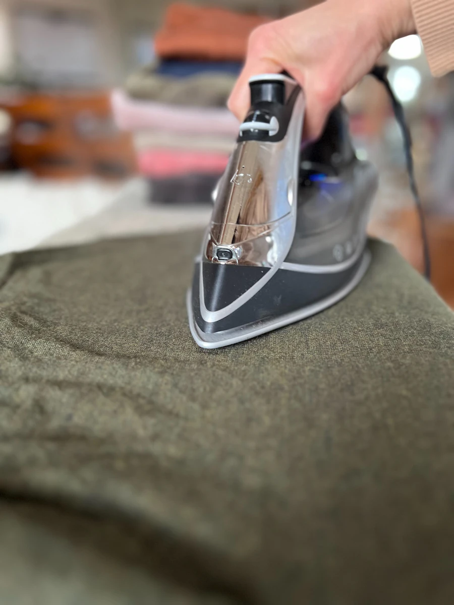 Steam iron pressing a green garment