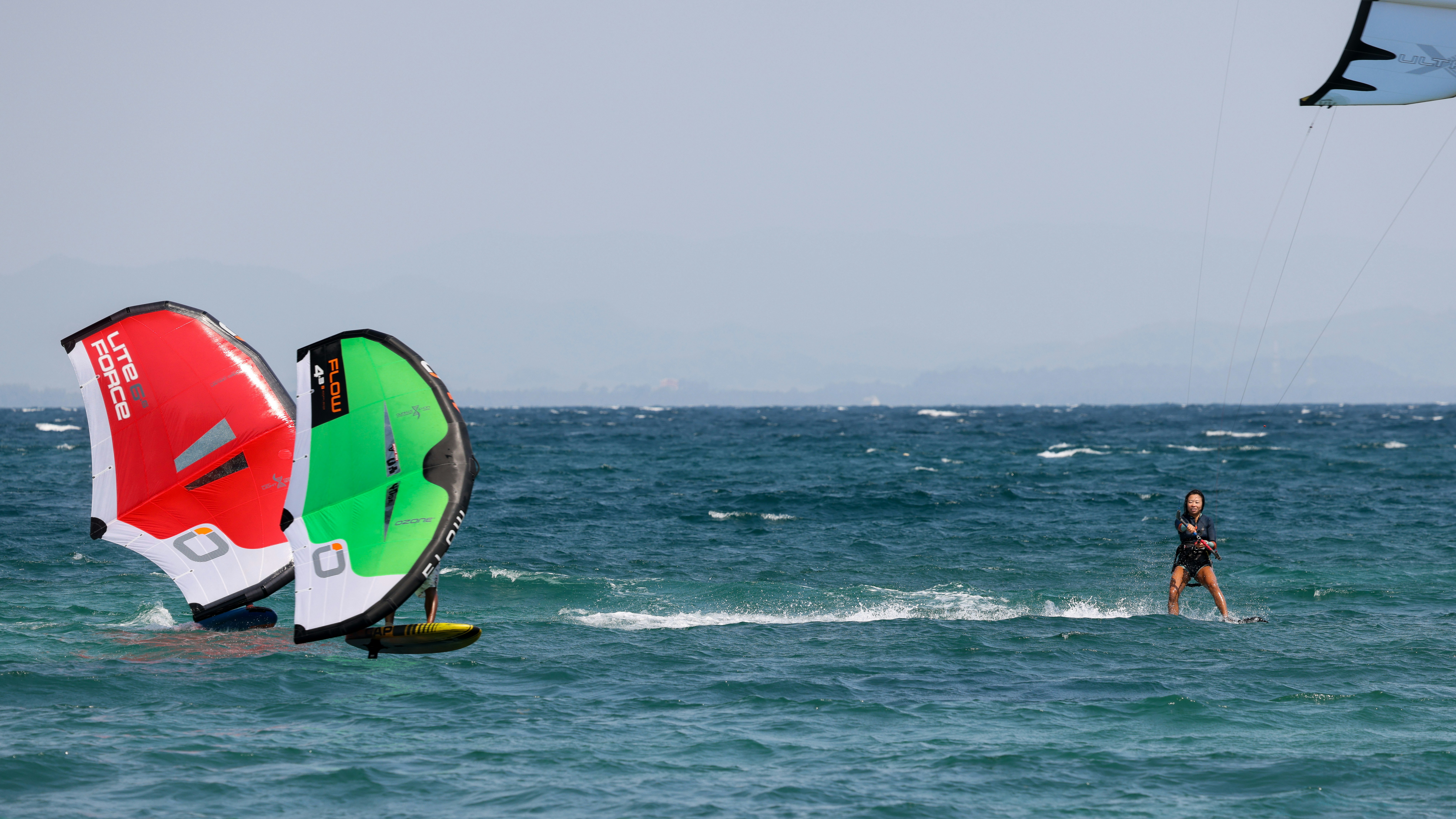 A couple of people are windsurfing in the ocean