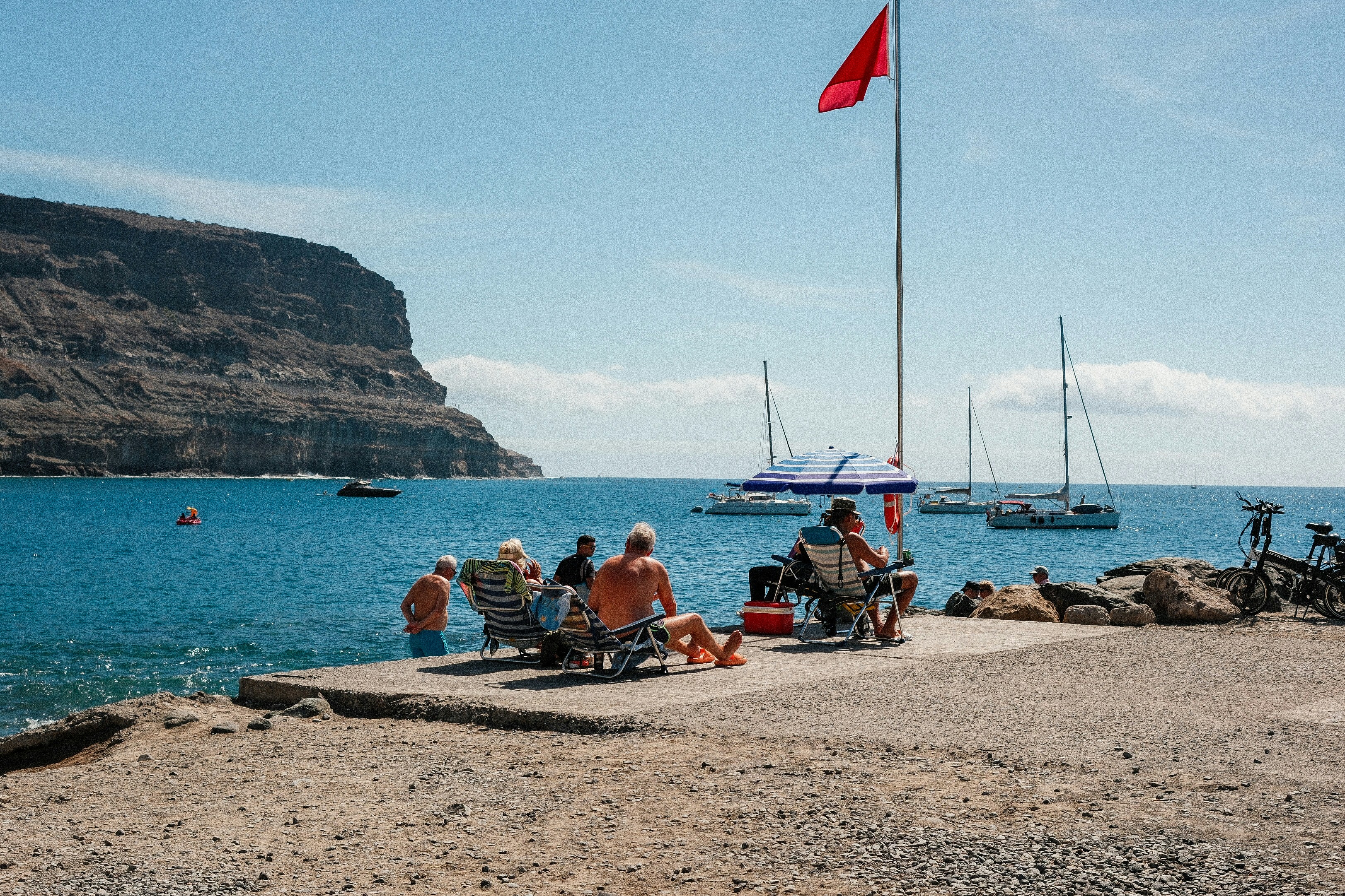 A group of people sitting on top of a sandy beach