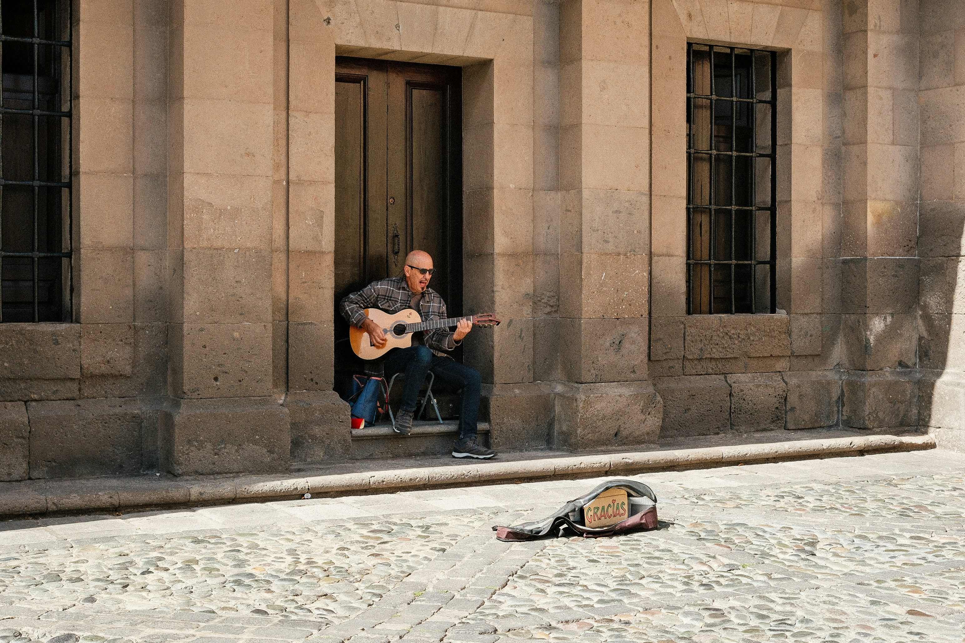A man playing a guitar in front of a building
