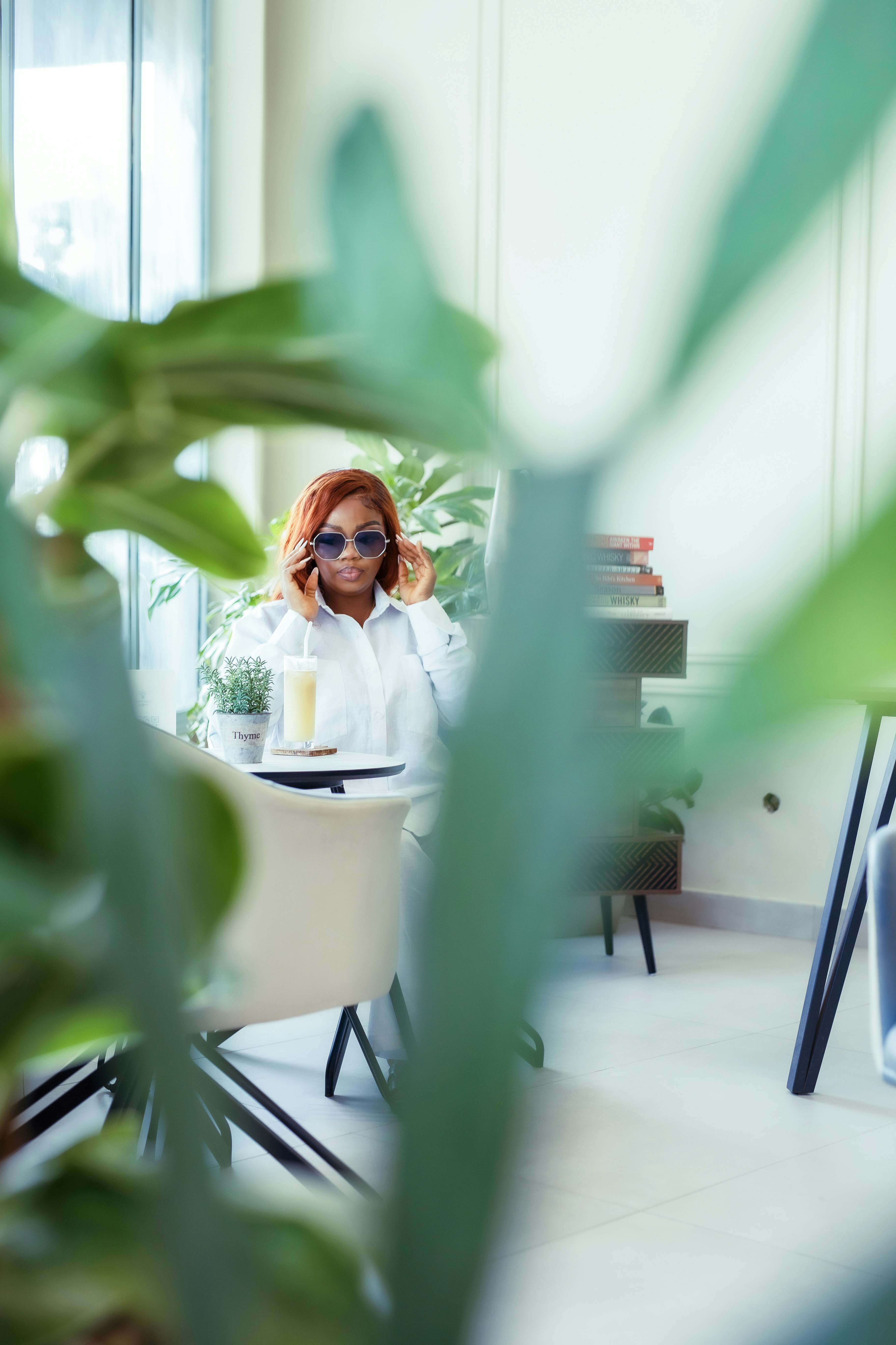 A woman sitting at a table with a plant in front of her