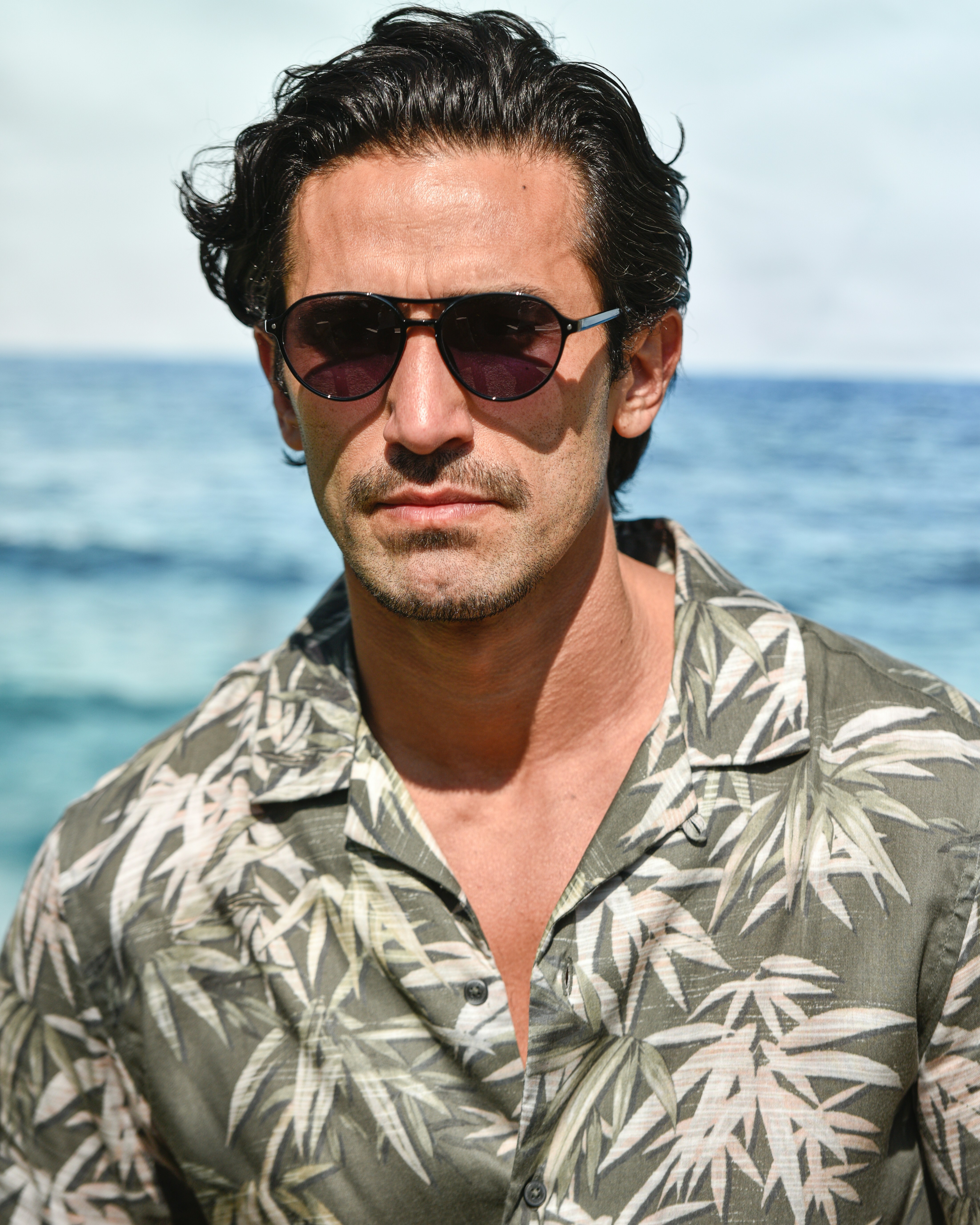 A man wearing sunglasses standing in front of the ocean photo – Free ...