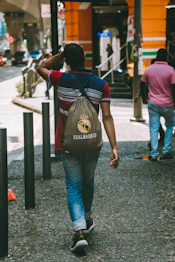 A man walking down a sidewalk with a bag on his back