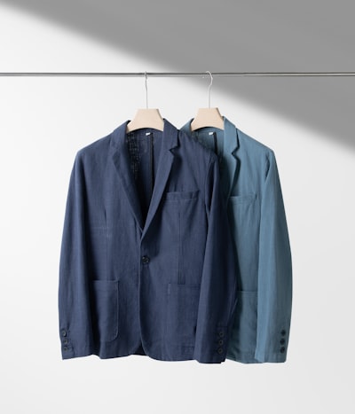 Linen blazers hanging against a light wall — photo by Robert Richman on Unsplash