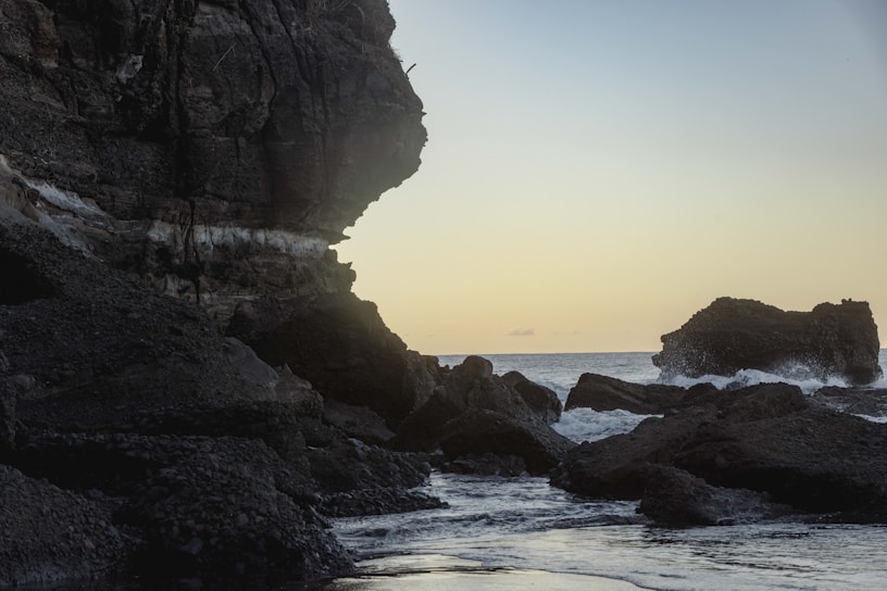 A person standing on a rocky beach next to the ocean