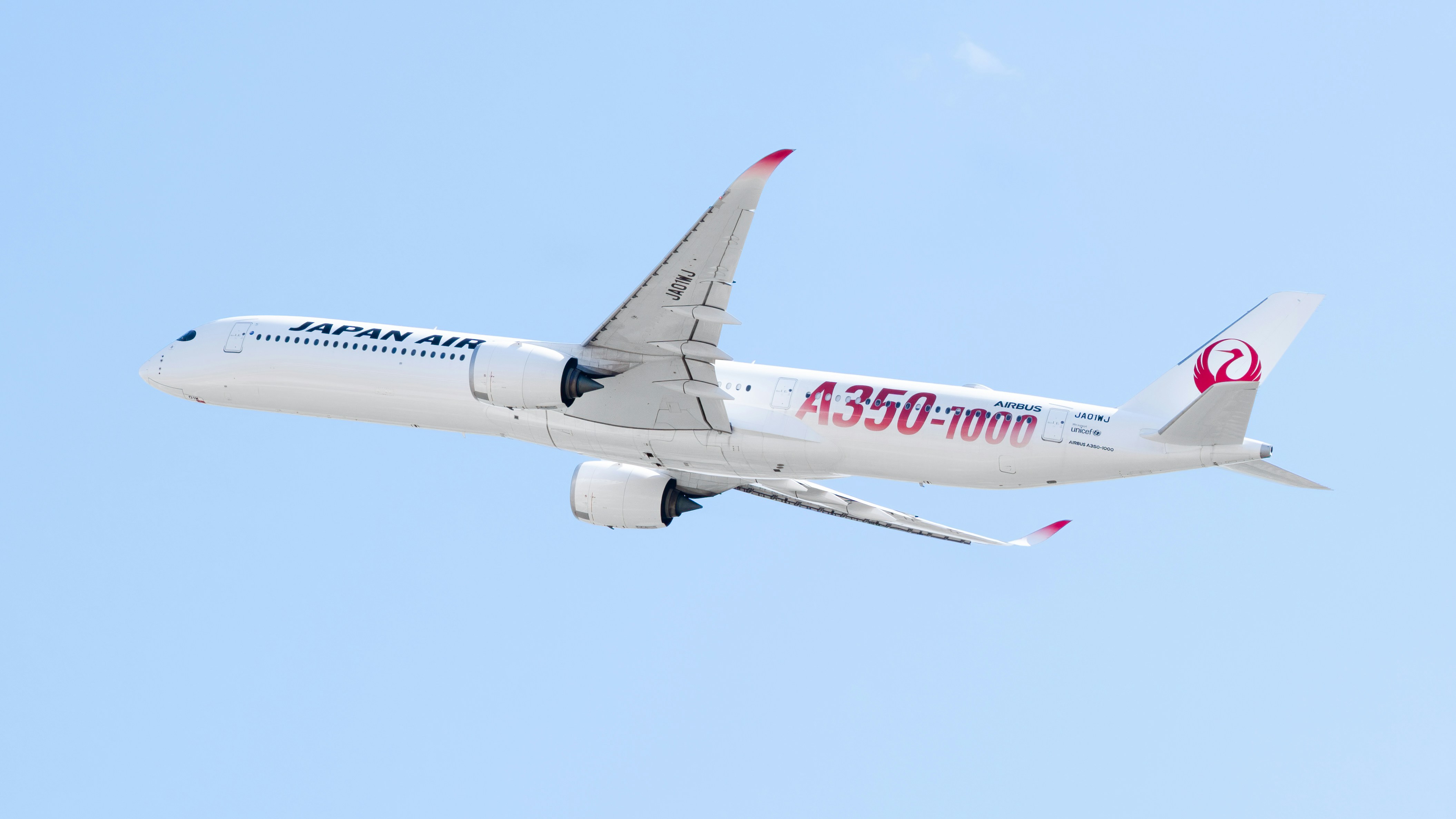 A large jetliner flying through a blue sky, Japan Airlines 1st Airbus A350-1000 in the special "Airbus Red Decal" livery. Taking off from Dallas Fort-Worth International Airport to Tokyo-Haneda.