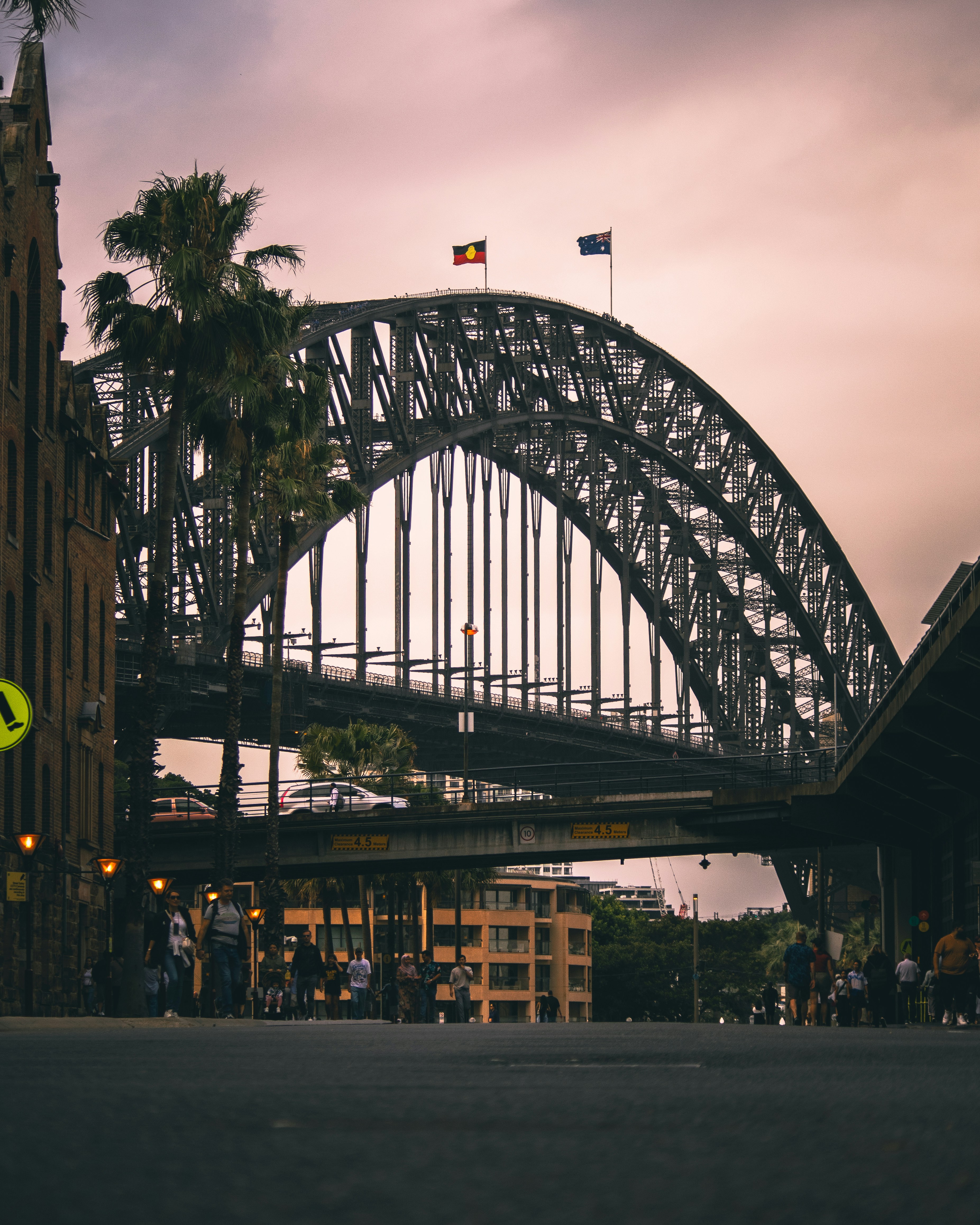A man riding a skateboard down a street next to a bridge