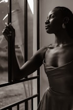 A woman in a dress leaning against a window