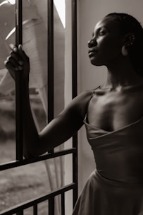 A woman in a dress leaning against a window