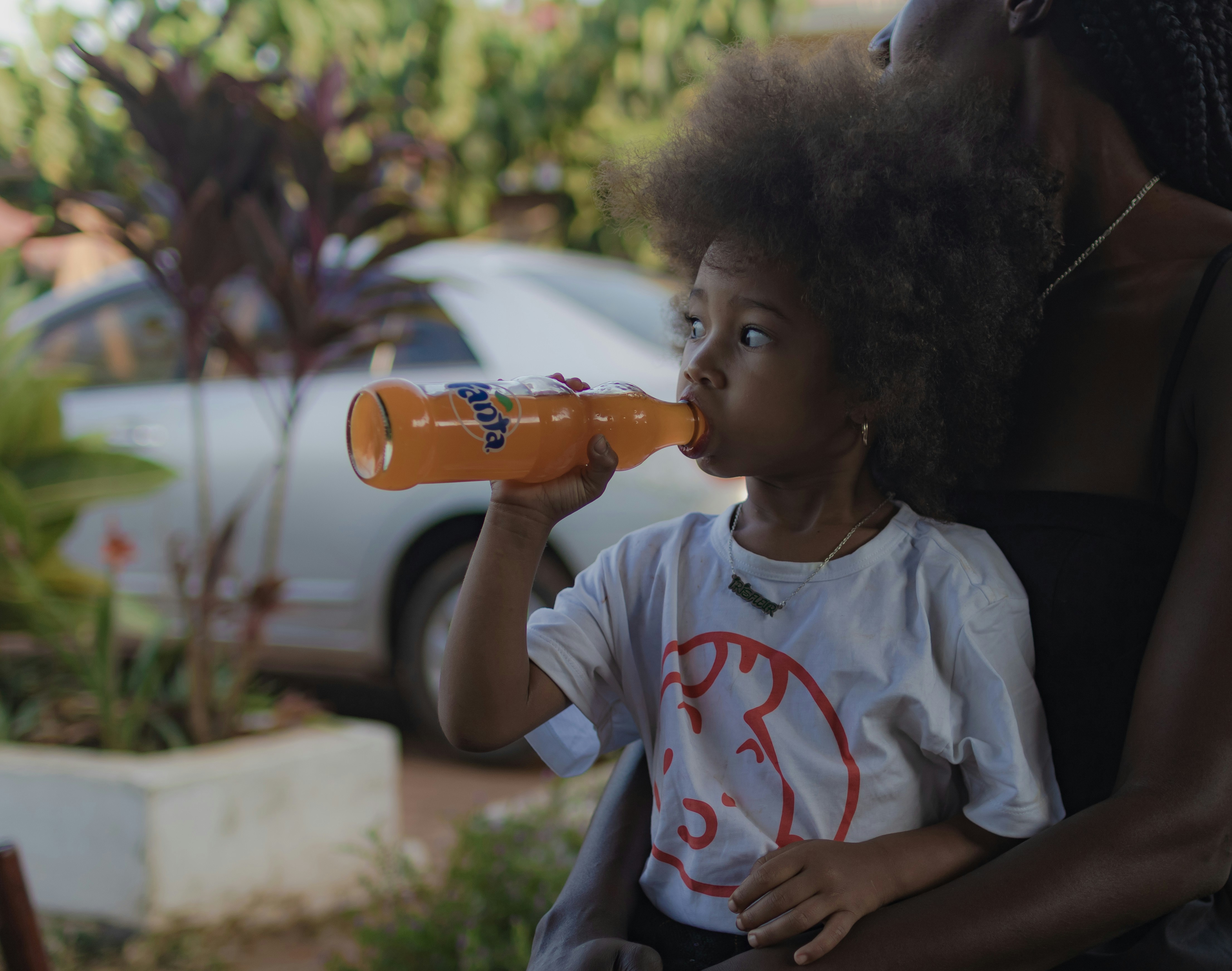 A woman holding a child and drinking from a bottle